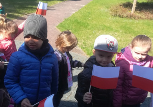 Dzieci maszerują z flagami.